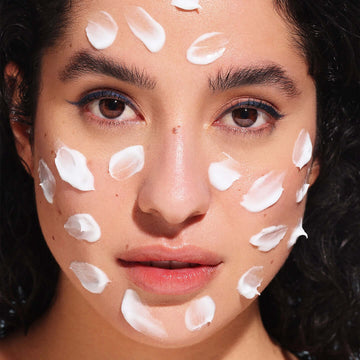 The girl covered her face with multiple dots of Face moisturizer for dry skin & glowing skin